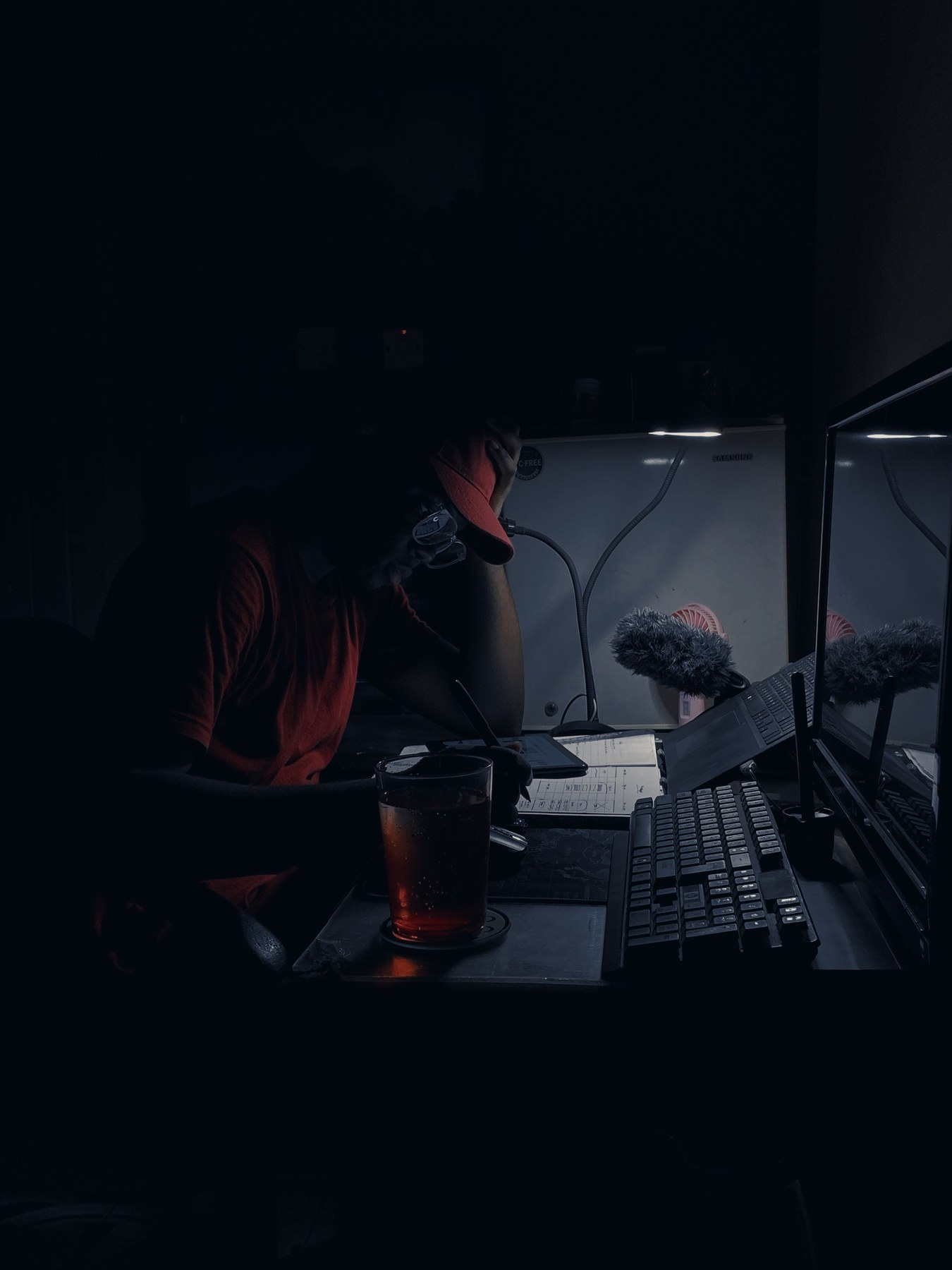 A man works alone late at night at a cluttered desk, lit by a single lamp — the quiet, unseen grind behind every comeback.