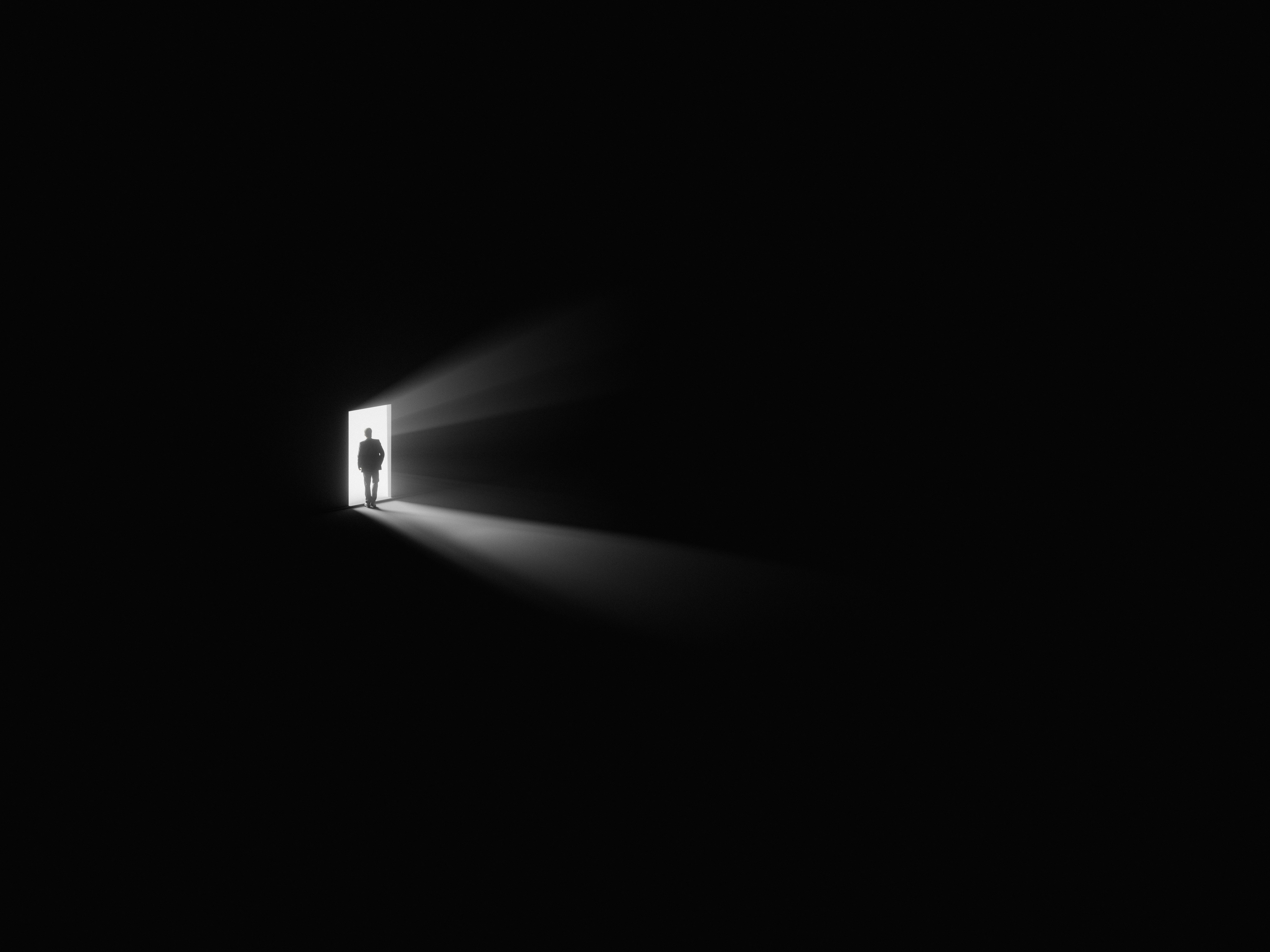 Man standing in a doorway — darkness behind, white light ahead