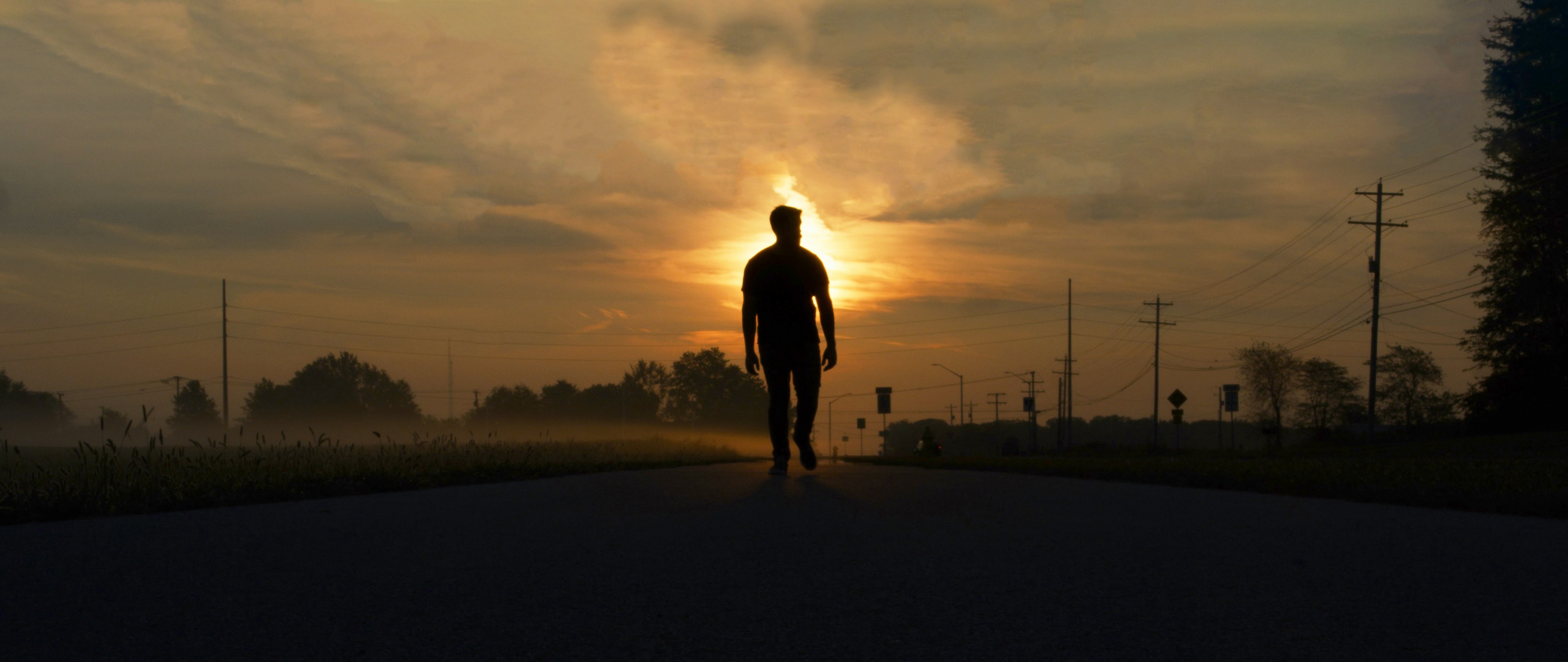 Man walking alone on a road at sunrise